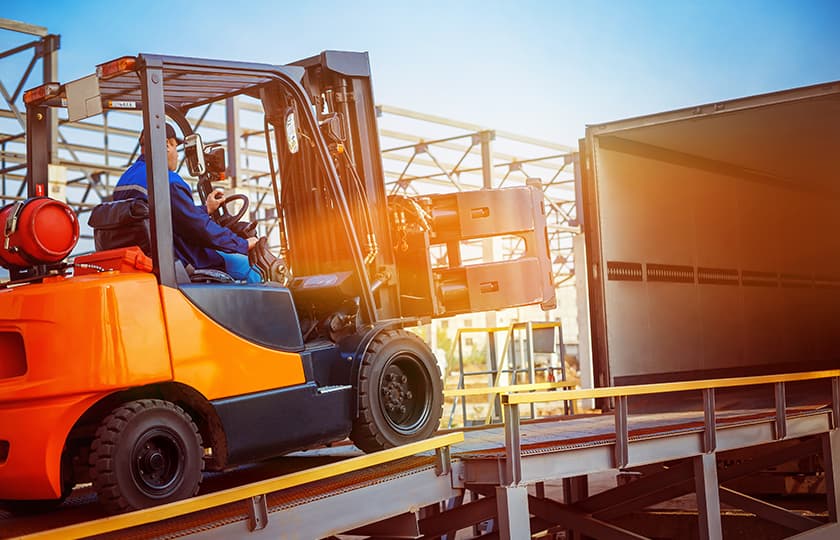 Forklift going up the ramp of a truck.