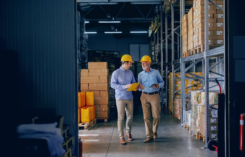 Business partners wearing safety helmets discussing operations in a warehouse