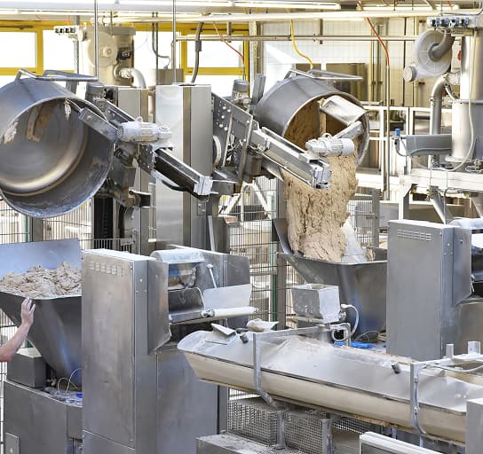Worker operating kneading machines on a bread production line in a large bakery