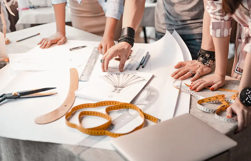 People stood around a table looking at product drawing to create a new product.