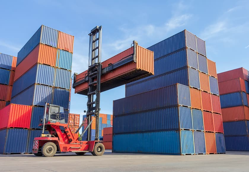 Forklift loading a container box onto a truck in a shipping yard