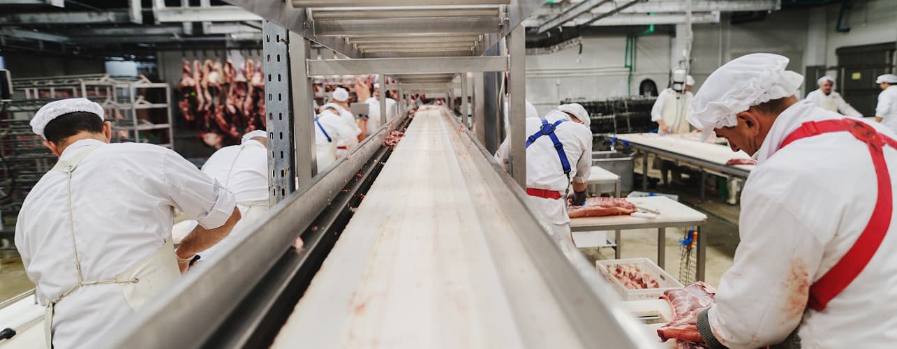 Workers handling meat for packing and shipping in a meat factory