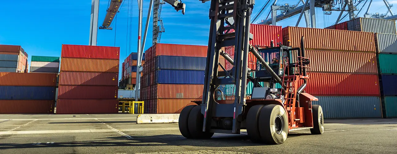 Forklift on the dock with containers in the background.