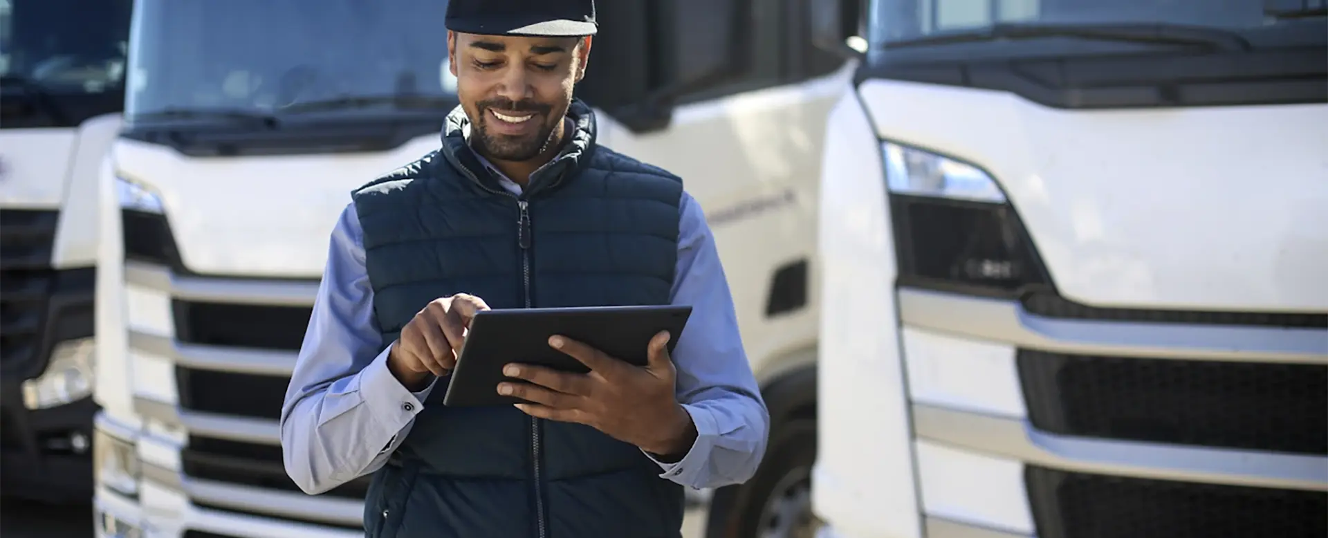 Man standing at truck med looking at tablet.