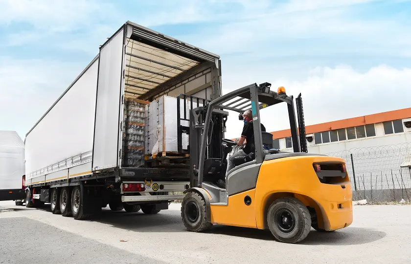 A forklift loading pallets onto a truck.