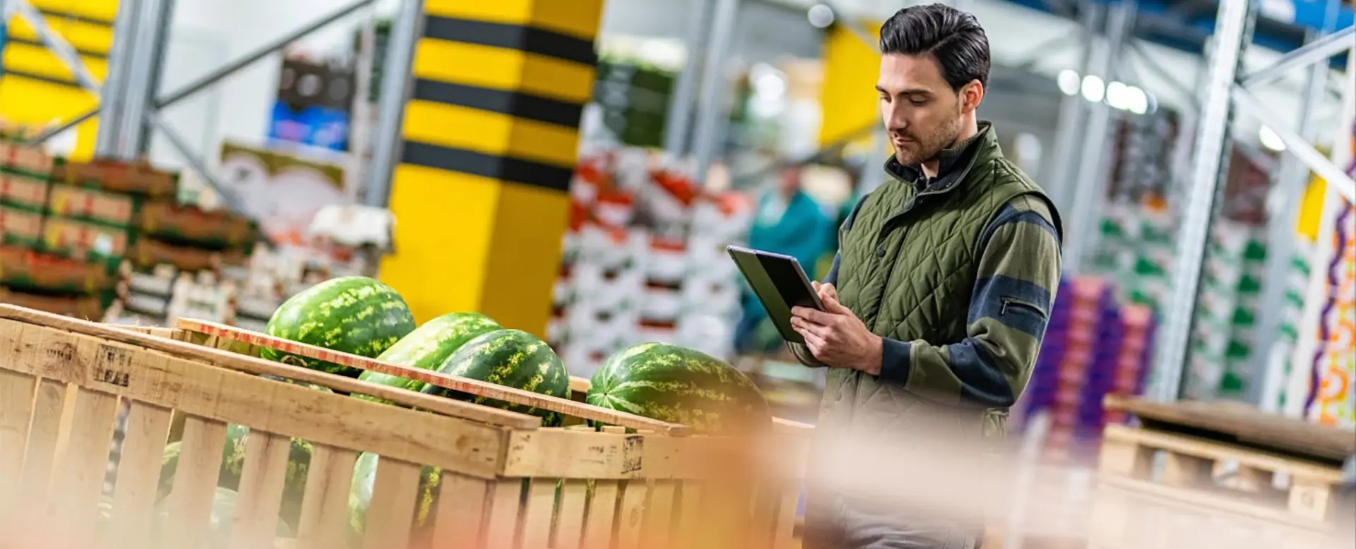 A fresh produce warehouse employee records information on a tablet.