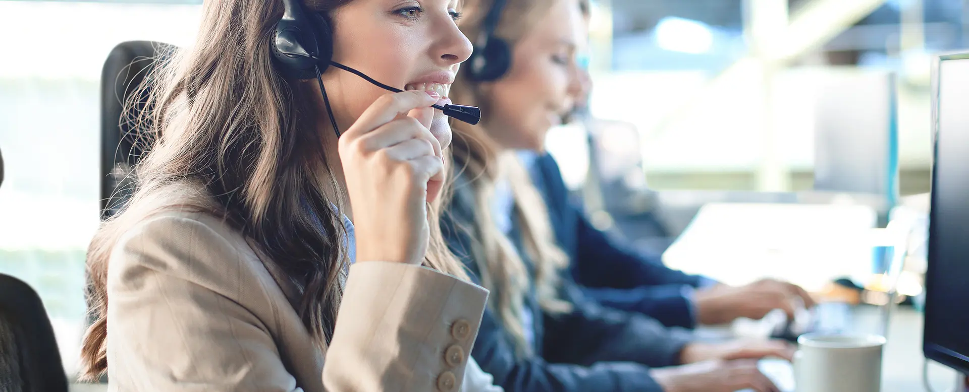 Female customer support operator smiling with colleagues in the background