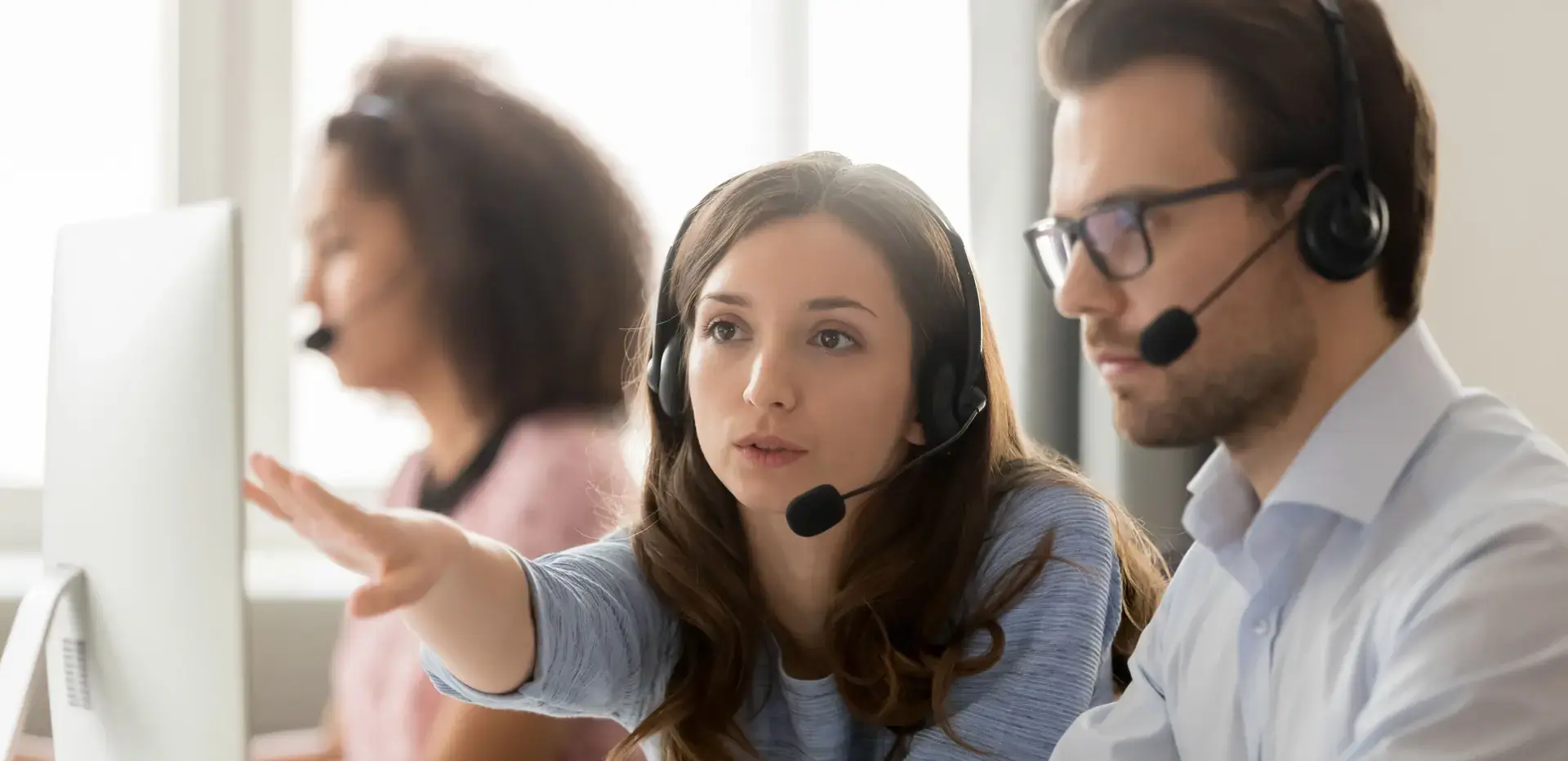 Call centre worker helping a new employee at a customer support desk