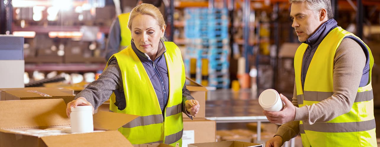 Workers packing boxes around a table in a warehouse