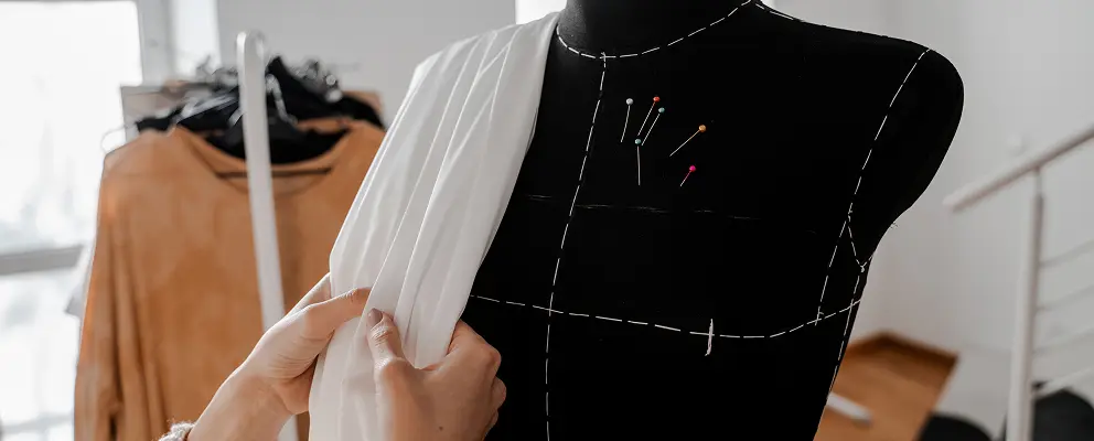 Fashion designer draping fabric on dress form mannequin in studio