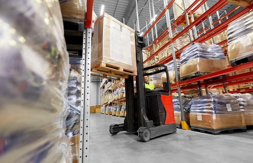 Forklift operator moving cargo inside a warehouse