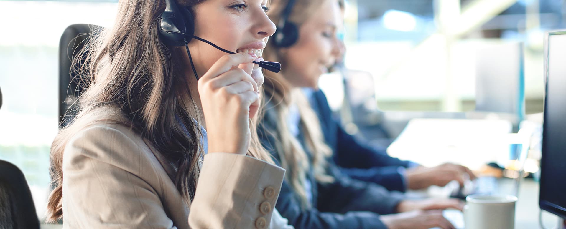 Female customer support operator smiling with colleagues in the background