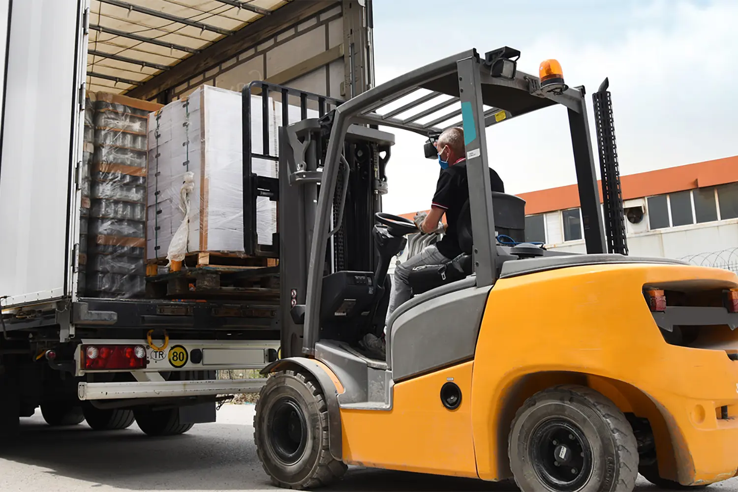 Forklift loading cargo goods into a truck for warehouse shipment