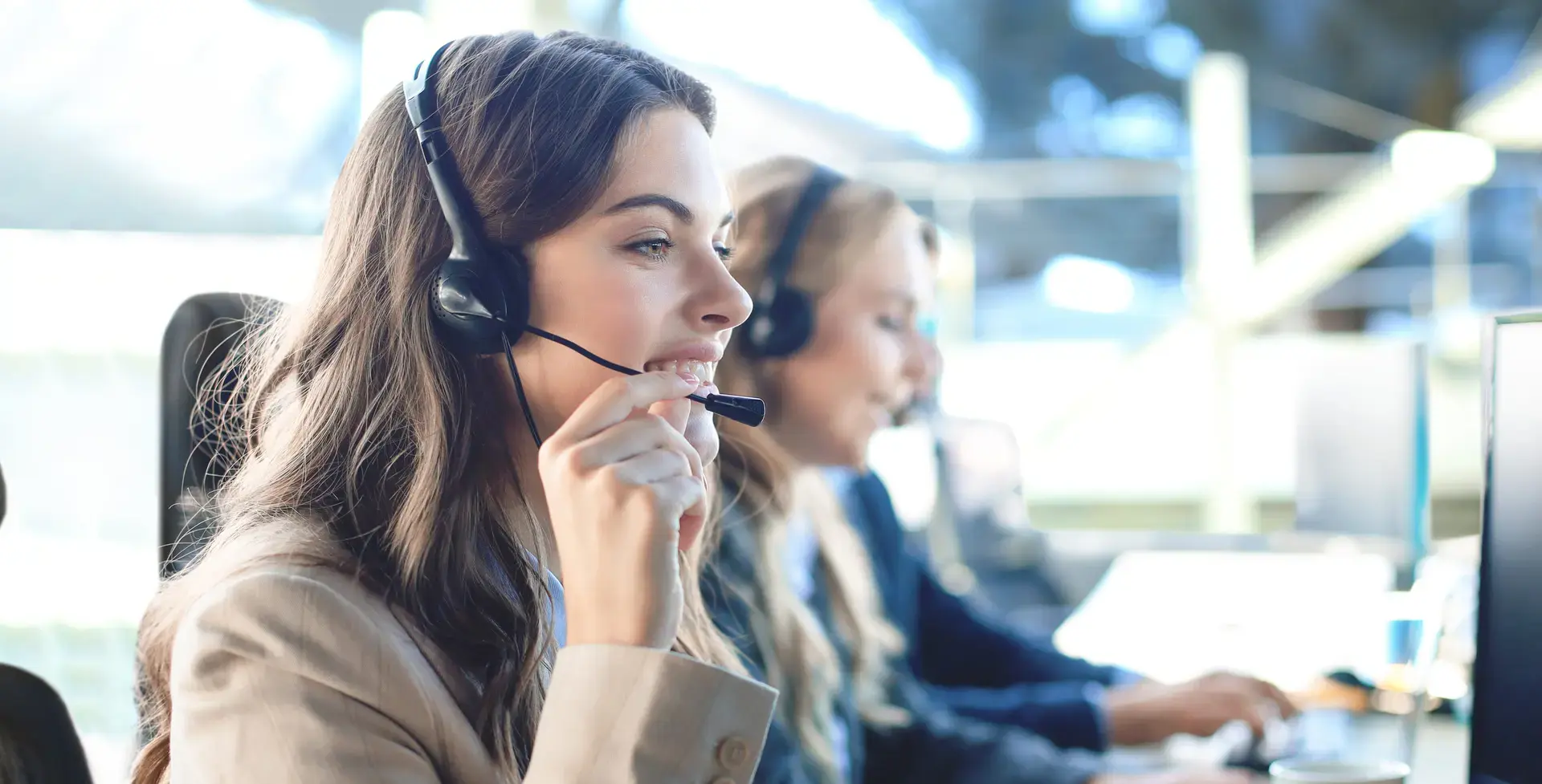 Female customer support operator smiling with colleagues in the background